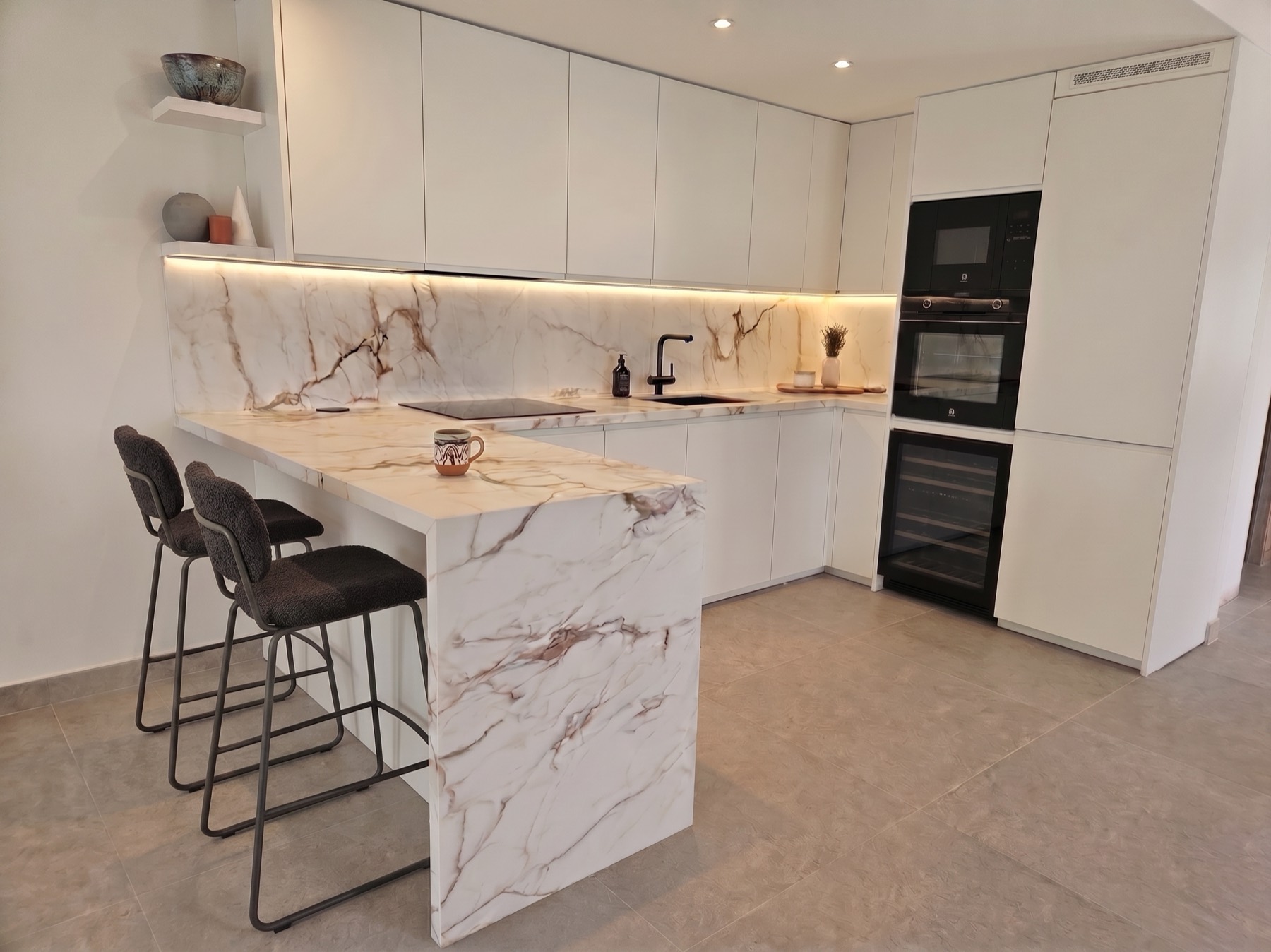 Cocina blanca con península de mármol y taburetes